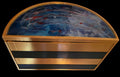 A rectangular storage box with a domed lid featuring a blue, white, and red marbled resin design, framed in gold-toned metal. The front of the box has three horizontal black panels with gold-toned metallic borders.